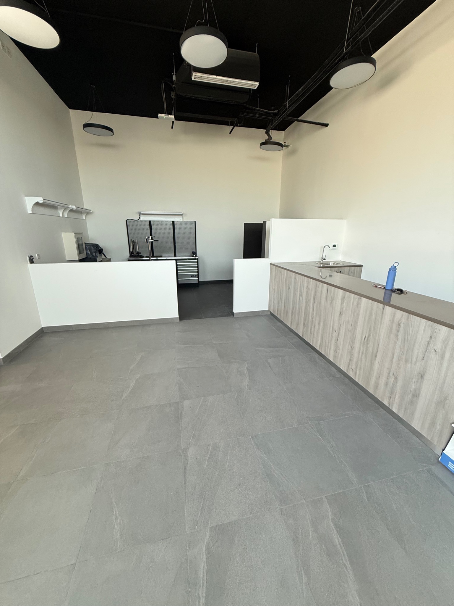 Existing CHAIN interior with an exposed ceiling, counter and workshop area towards the back